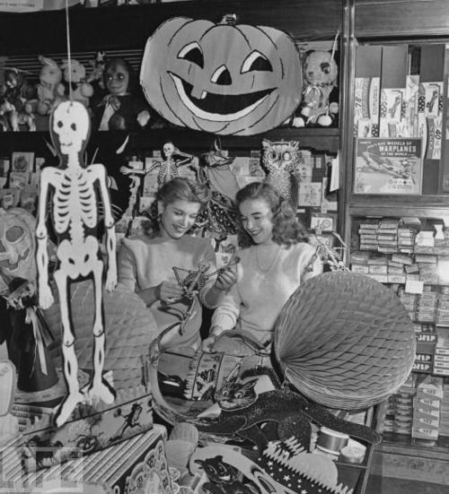 1940s vintage photo of a Halloween decorations in a store with two young women in 1940s hairstyles browsing the decor.