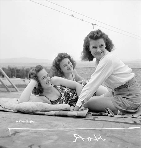 1940s vintage photo of 3 women taking a break after working in the factory. They are catching some sun in 1940s swimsuits and 1940s summer fashions. Cute 1940s hairstyles. 