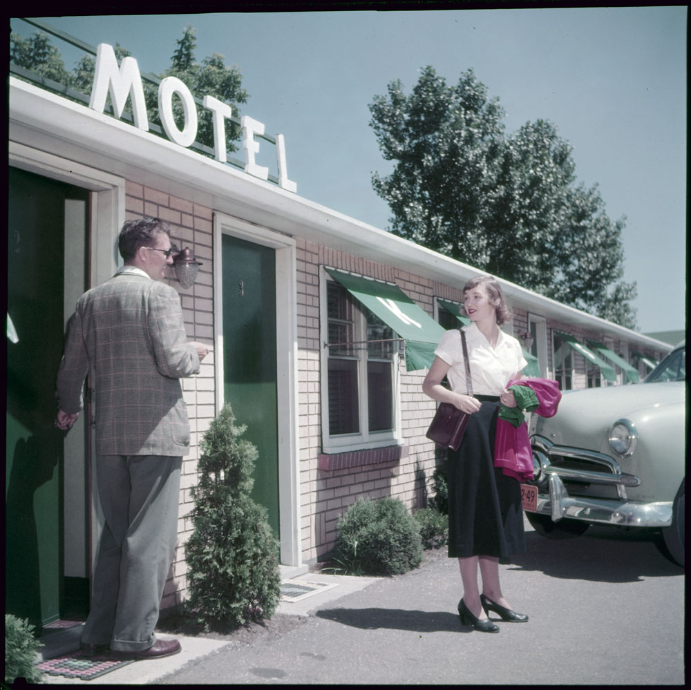 1950s vintage image motel in niagara falls canada featuring a couple in 1950s fashions coming out of a mid century motel. 