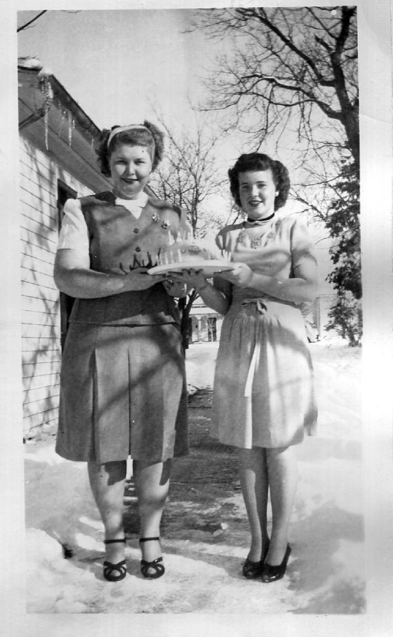 1940s vintage image of 2 women celebrating a birthday in the winter in 1940s fashions and 1940s hairstyles.
