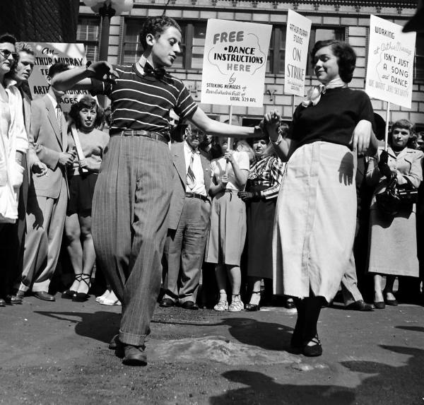 1940s Vintage Image of the Dancing Teachers Strike 1947 featuring a couple dancing together with picket signs in the background. 