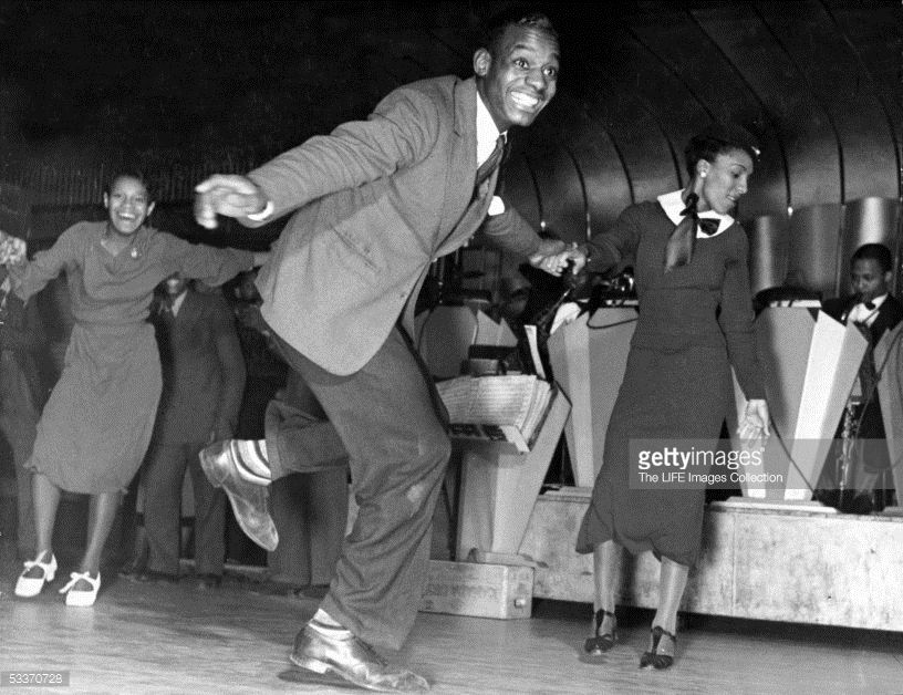 1930s vintage photo of Lindy Hoppers at the savoy ballroom in 1930s fashions dancing.