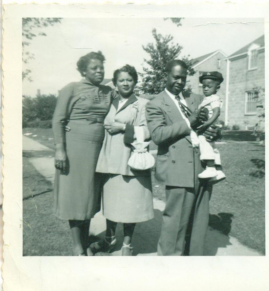 1940s vintage photo of a Black family posing together for a photo in stylish 1940s fashions. 