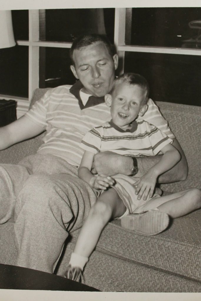 1950s photo of a father and son sitting on a couch. Mid-Century vintage photo. 