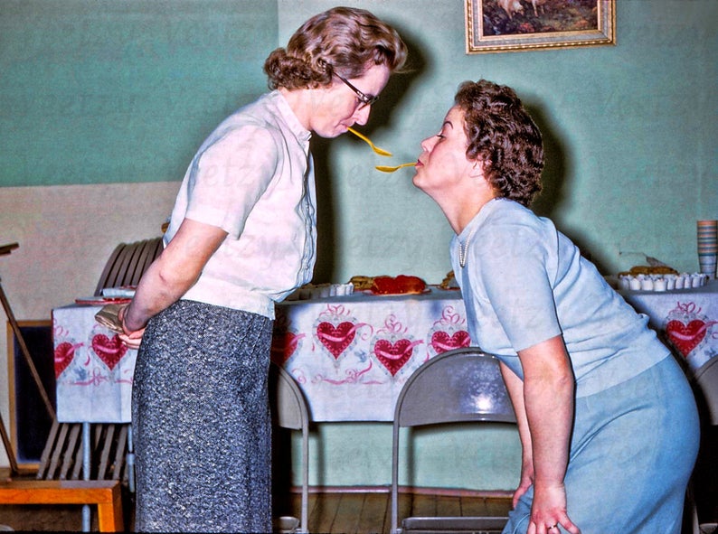 1950s Party games for adults a spoon game. Image features 2 women in 1950s fashions playing a 1950s party game. 