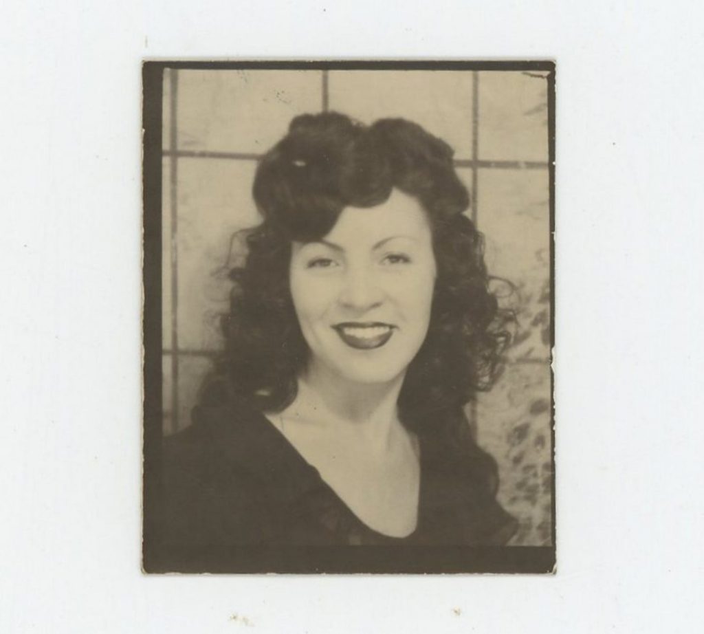 Photo Booth Beauty, c1940s Vintage Photo of a young woman with a 1940s hairstyle and red lipstick posing for photo in a photobooth. 