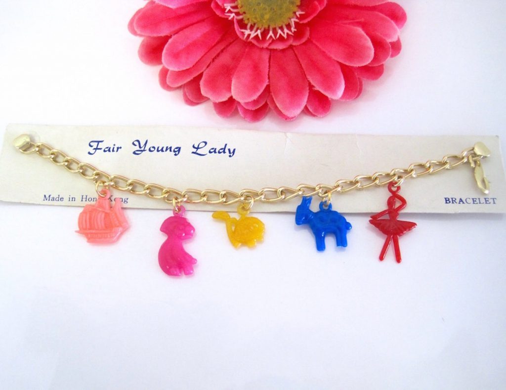vintage child's charm bracelet has 5 colorful plastic charms dangling from a gold-tone curb link chain bracelet.