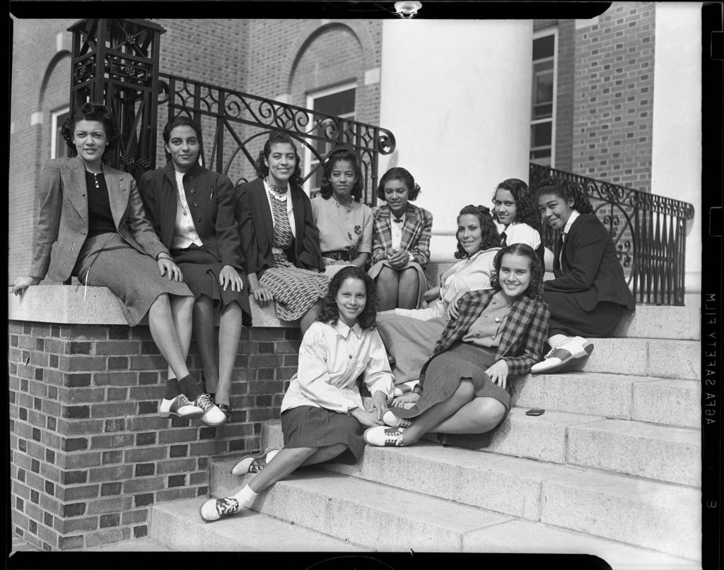 Late 1930s Vintage Photo of a Group portrait of ten Black women, including several wearing saddle shoes, gathered on steps of brick building with large pillars