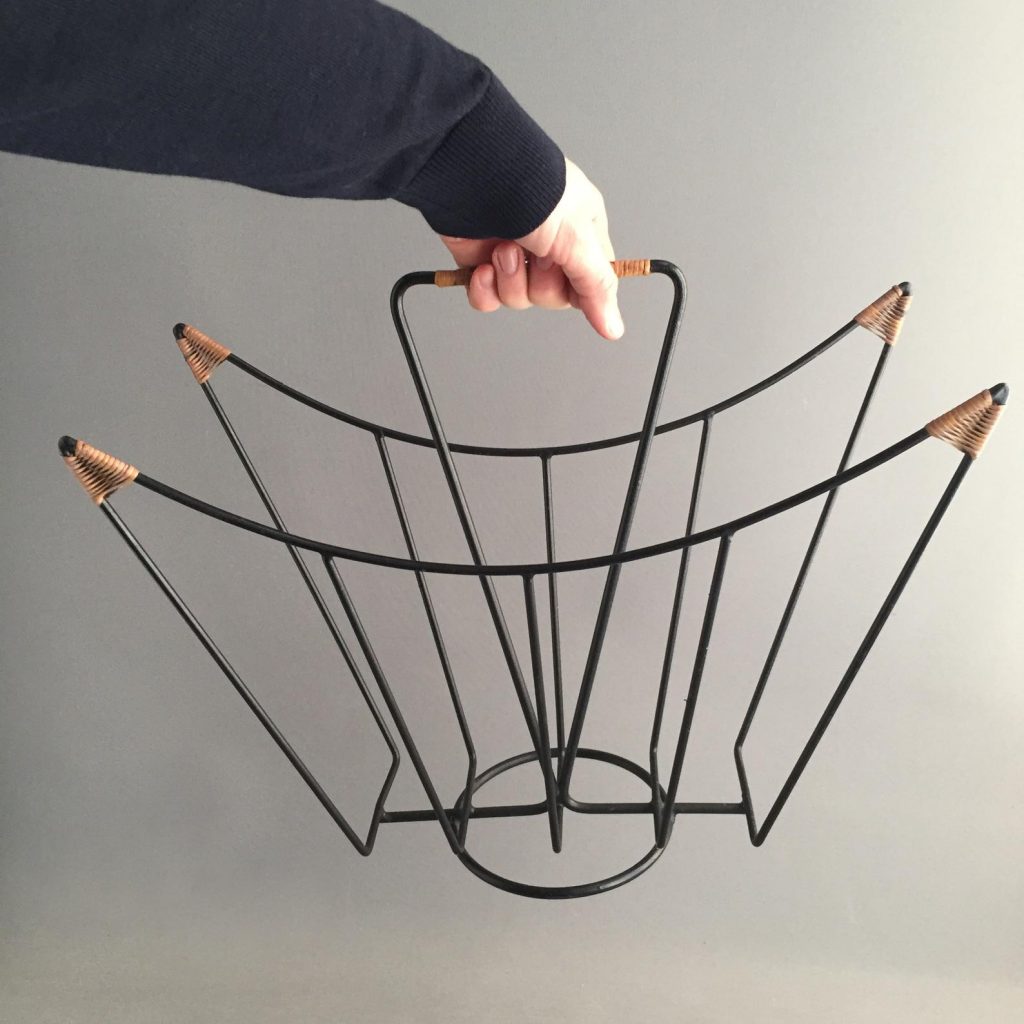 1950s vintage solid black metal magazine rack with decorative rattan detail on the handle and all 4 corners.