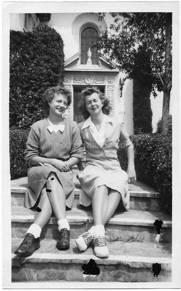 1940s photo of 2 women in 1940s fashions, 1940s hairstyles, saddle shoes sitting together for a photo 