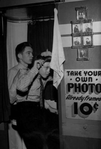1950s vintage photo of 2 young men getting ready to take photos in a photo booth