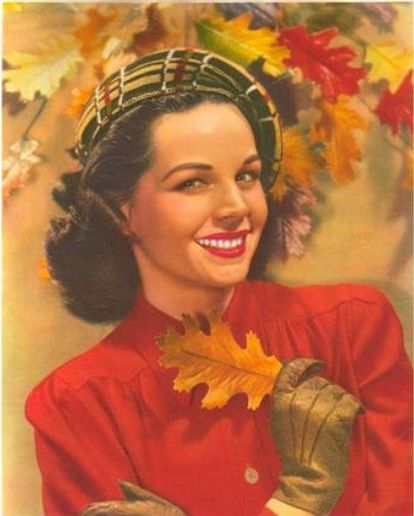 1940s vintage image of a 1940s woman with a 1940s hat and 1940s hairstyle holding a Fall leaf in her gloved hand. Vintage Fall image. 
