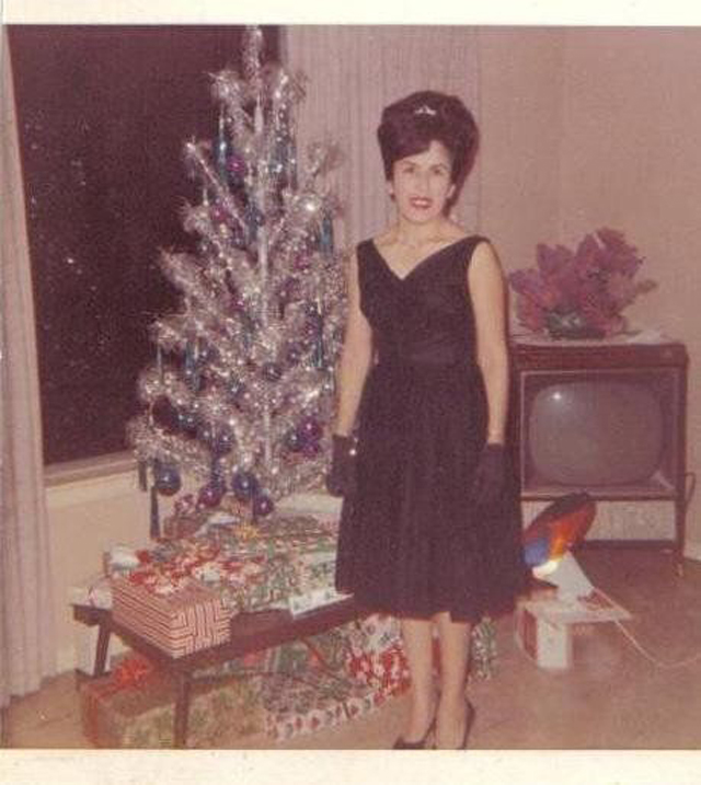 1960s vintage photo of a woman in a black 1960s cocktail dress posing in front of her Aluminum Christmas Tree with color wheel