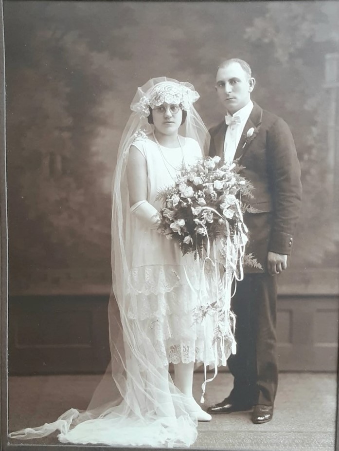 https://www.vintageinn.ca/wp-content/uploads/2023/04/1920s-vintage-wedding-photo-of-a-1920s-bride-with-glasses-posing-in-her-1920s-wedding-dress-with-her-1920s-groom.jpg