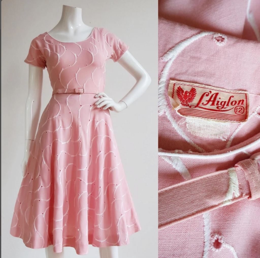 1950s Fashion: 1950s soft pink cotton/linen dress by L’Aiglon features broad wisps with Broderie anglaise, rounded neckline, fitted waist and a flirty full skirt with single hip pocket.