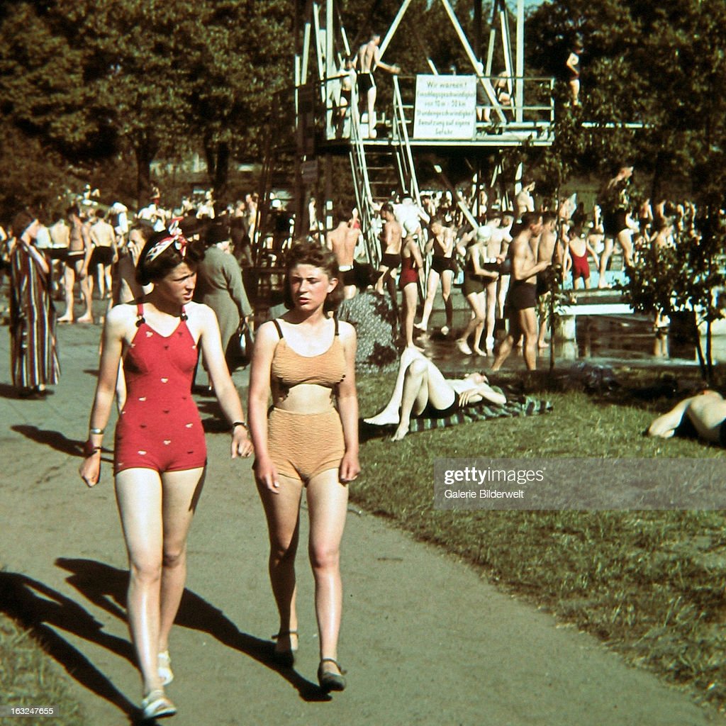 1930s vintage photo of Cologne 1939.
Two girls in bathing suits are walking from the swimming pool, where people are engaged in various activities. 1939. 