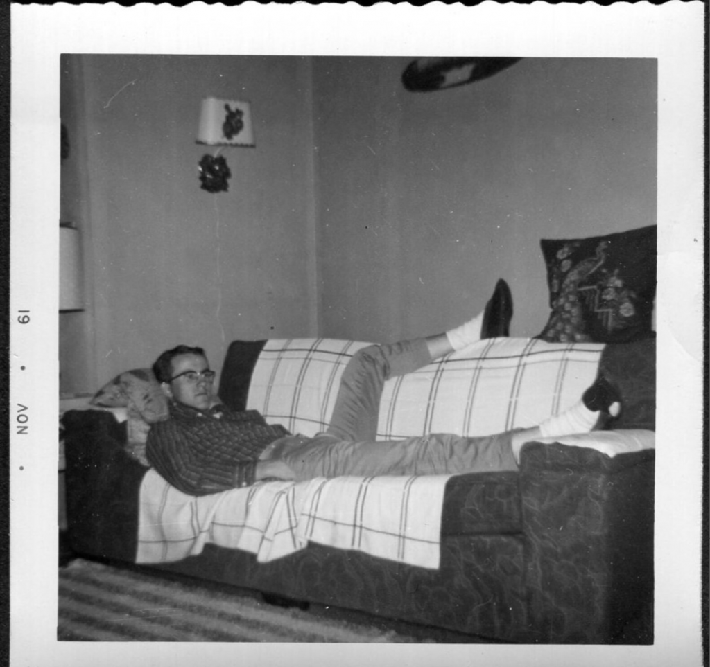 1960s vintage photo from November 1961 of young man relaxing on his couch. 