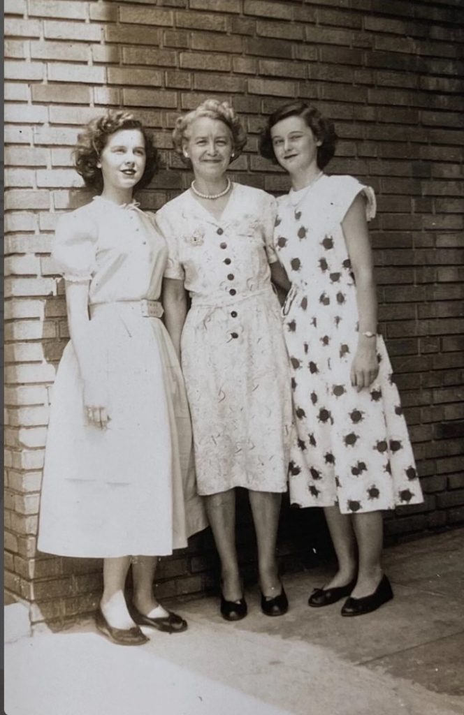 1940s vintage photo from 1948 of an older mother posing with her two daughters in 1940s dresses and 1940s hairstyles