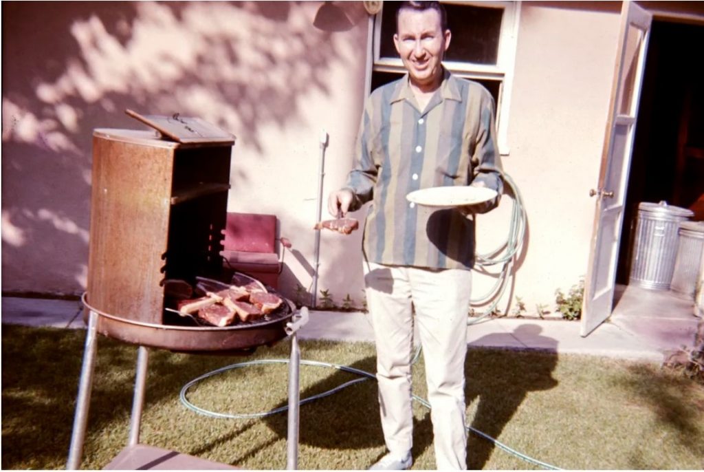 1950s vintage photo of a man grilling steaks in his backyard