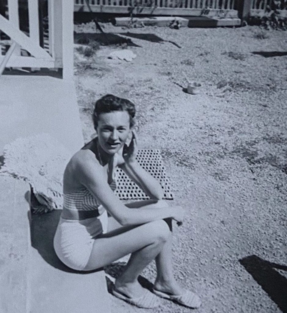 1950s vintage photo of a young woman in short shorts sitting on the front porch looking at the camera