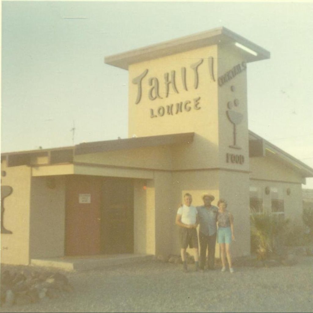 1960s vintage photo of a couple in shorts posing in front of a bar / restaurant called 'The Tahiti Lounge' and it has great Mid-Century Typography on the sign.
