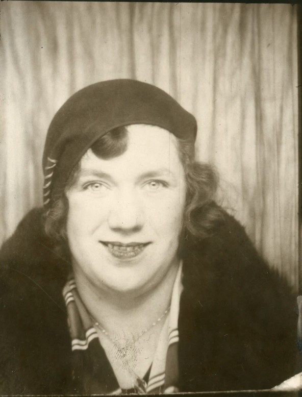 1930s vintage photo of a woman in a photo booth wearing a beret which was a popular 1930s hat style for women. She is also wearing a short 1930s bob vintage hairstyle. 
