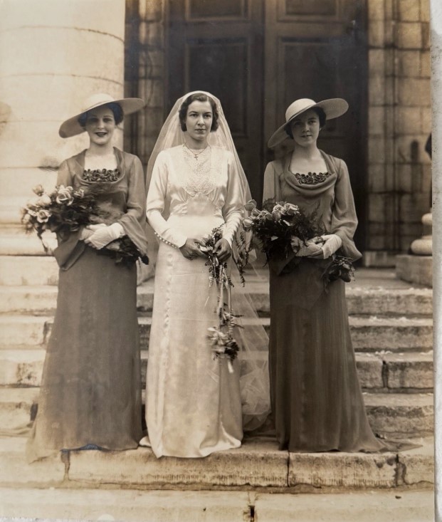 1930s vintage photo of a 1930s bride in her wedding dress posing with her bridesmaids in 1930s dresses and hat. Stunning 1930s wedding fashions. 