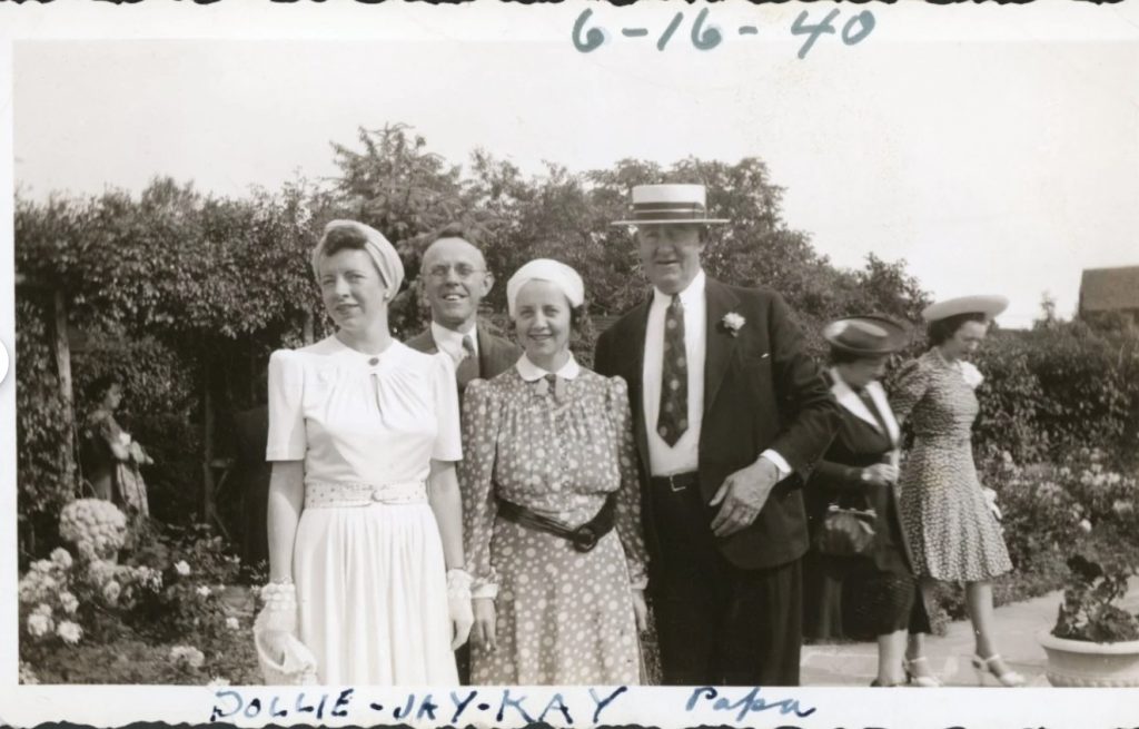 Early 1940s vintage photo of a group of men and women in early 1940s fashion (1940) out in a garden during the summer wearing early 1940s dresses, suits and 1940s hats for women and men. 