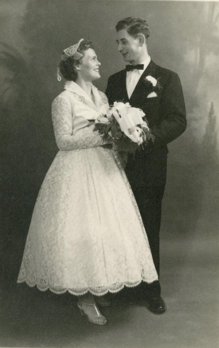 1950s wedding photo of the bride and groom featuring a pretty 1950s lace tea length wedding dress. 