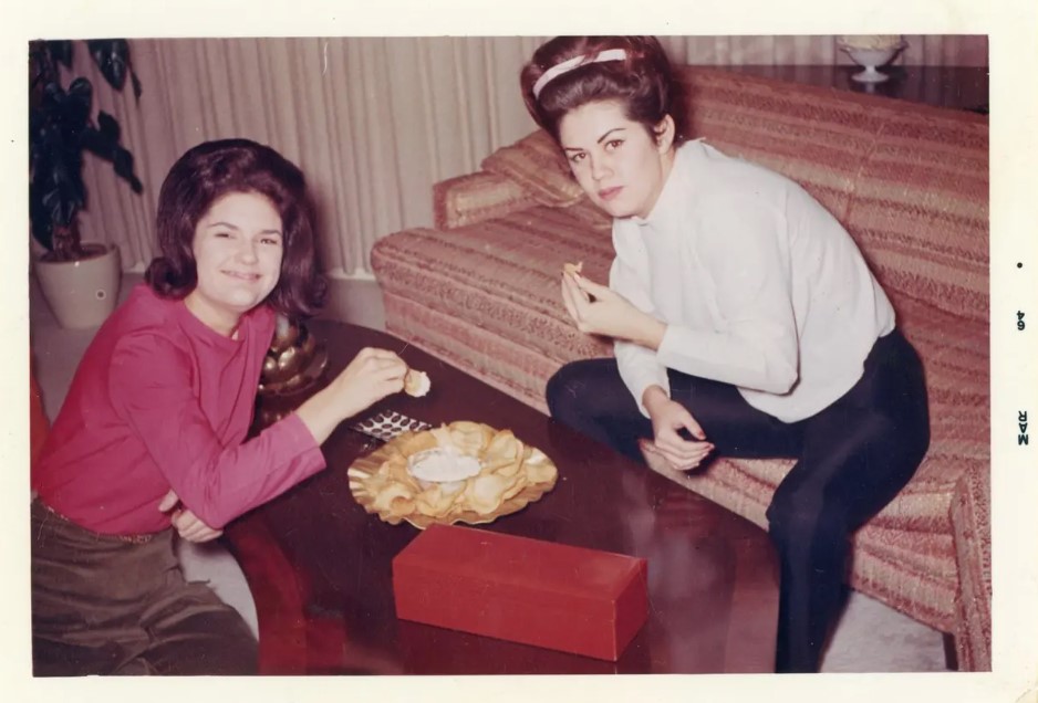 1960s vintage photo (march 1964) of two 1960s women with 1960s hairstyles enjoying chips and dip in a 1960s living room
