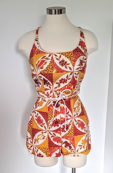 1960s Fashion / 1960s Summer Fashion: A 1960s Cole of California one piece swimsuit with a butterfly, drum and floral pattern and rope belt. 