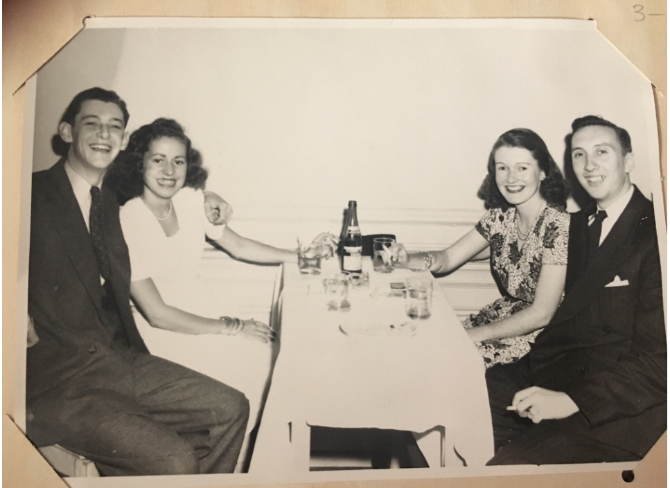 1940s vintage image of two couples posing together over drinks at the King Edward Hotel in Toronto, Canada. They are wearing 1940s fashions. 