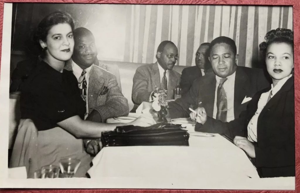 1940s vintage photo of a group of stylish Black Women and Black Men having a smoke and dinner together at the famous Cafe Zanzibar in New York City. 
