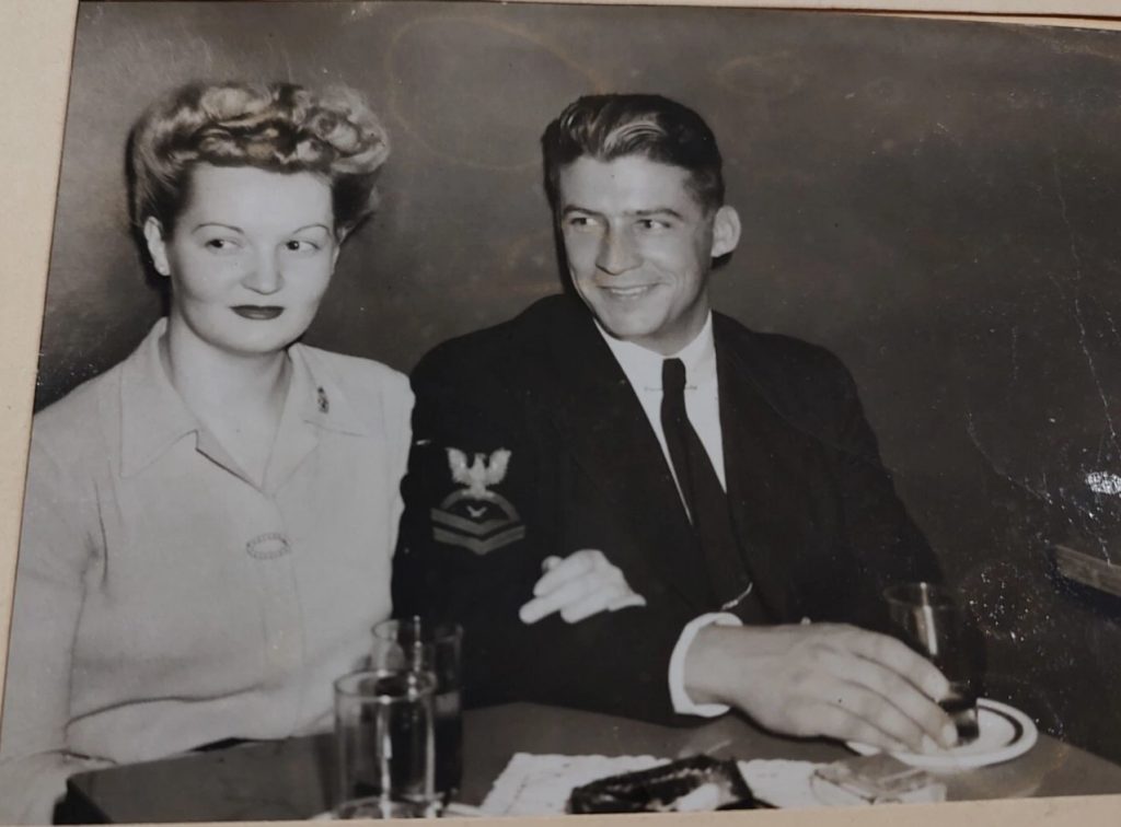 1940s vintage photo of a man in uniform and a woman in a pretty 1940s hairstyle pose together for a photo as they enjoy a cocktail at the Music Bar Cocktail Lounge in New York City. 