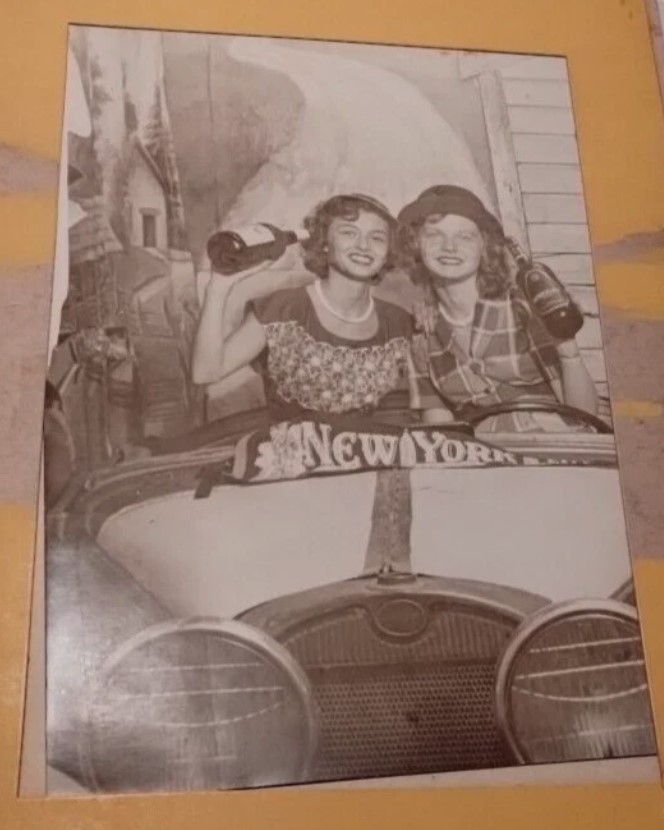 1940s fun vintage image / 1940s souvenir photo of two young Women posing in a car holding wine bottles. Cute 1940's dresses!